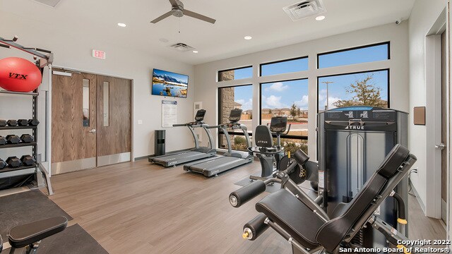 gym with light hardwood / wood-style flooring and ceiling fan