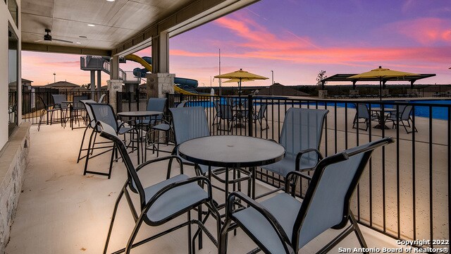 patio terrace at dusk with ceiling fan and a community pool