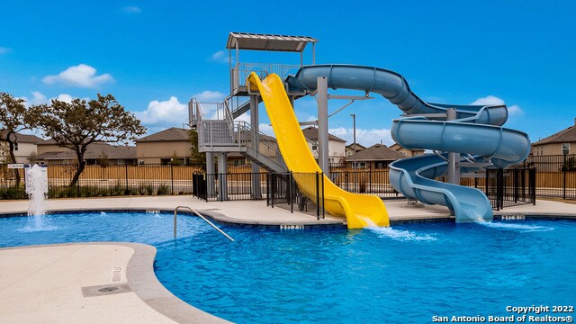 view of swimming pool with pool water feature and a water slide