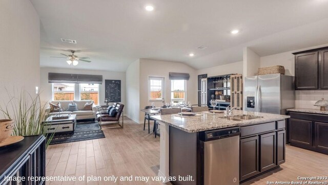 kitchen with ceiling fan, an island with sink, light hardwood / wood-style floors, decorative backsplash, and appliances with stainless steel finishes