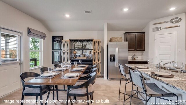 dining area with light wood-type flooring, sink, and vaulted ceiling