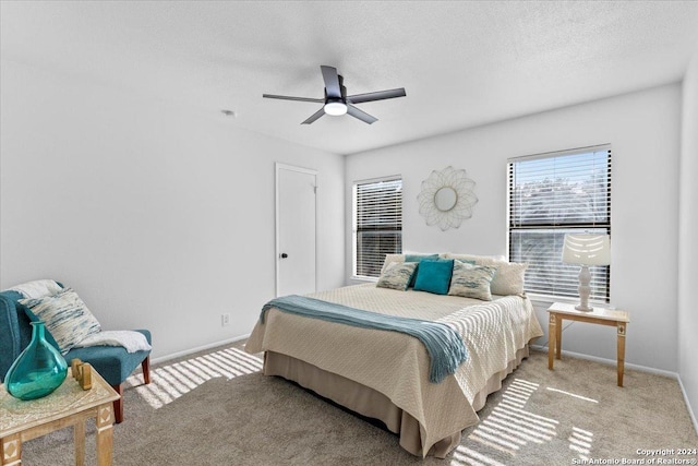 bedroom featuring light carpet, a textured ceiling, and ceiling fan