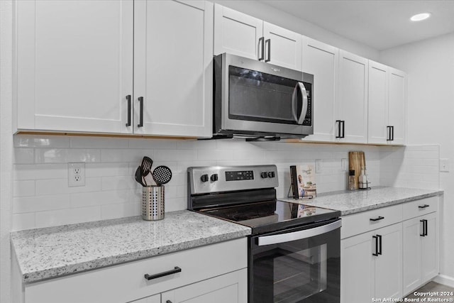 kitchen with tasteful backsplash, white cabinets, and stainless steel appliances