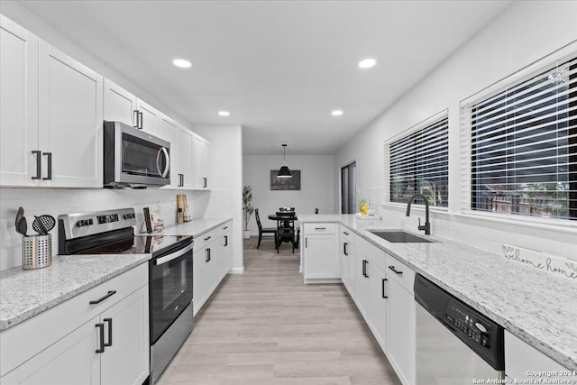 kitchen with pendant lighting, stainless steel appliances, white cabinetry, and sink