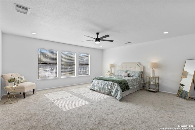 carpeted bedroom featuring ceiling fan and a textured ceiling