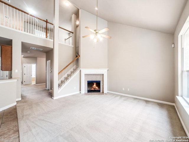 unfurnished living room with a tile fireplace, high vaulted ceiling, ceiling fan, and a healthy amount of sunlight