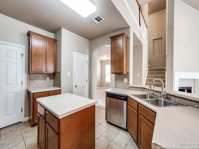 kitchen featuring dishwasher, sink, kitchen peninsula, a fireplace, and light tile patterned floors