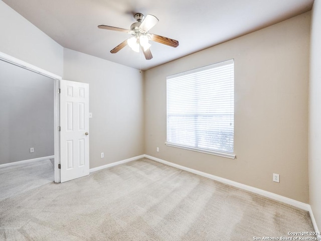 carpeted spare room with ceiling fan