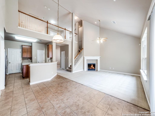 unfurnished living room featuring a fireplace, ceiling fan, light carpet, and high vaulted ceiling