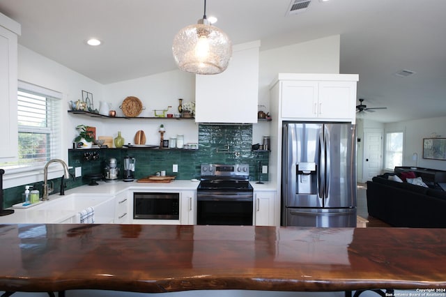 kitchen with pendant lighting, backsplash, sink, vaulted ceiling, and appliances with stainless steel finishes