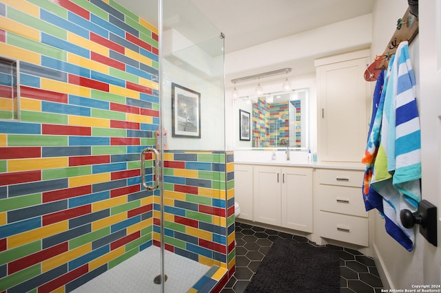 bathroom with tile patterned floors, a shower with door, vanity, and tile walls