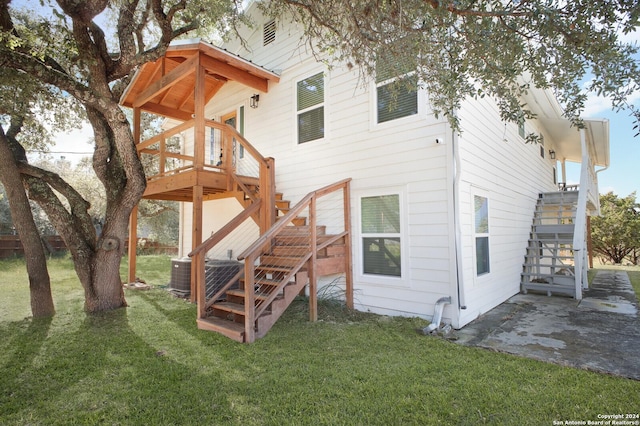 back of property featuring cooling unit, a deck, a yard, and a patio