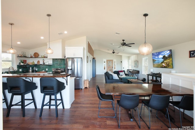 dining room with ceiling fan, dark hardwood / wood-style flooring, vaulted ceiling, and sink