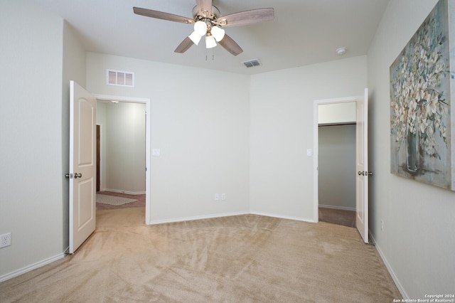 unfurnished bedroom with ceiling fan, a walk in closet, light carpet, and a closet