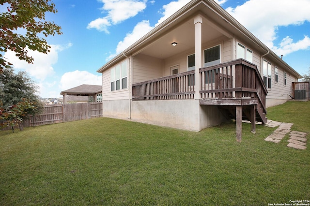 rear view of house featuring a yard, a wooden deck, and central air condition unit