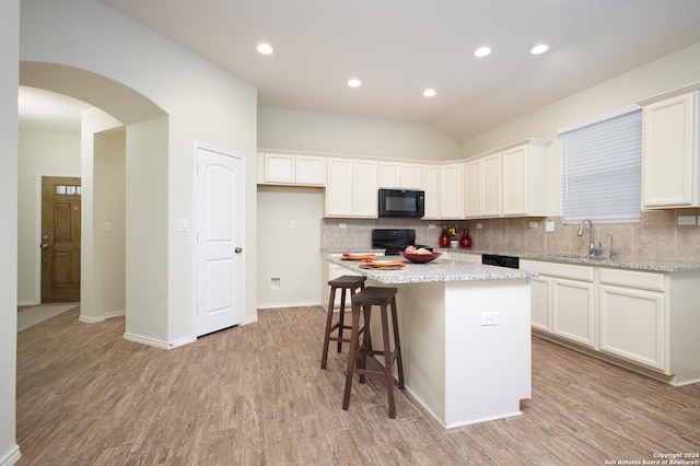 kitchen featuring black appliances, a center island, white cabinetry, and sink