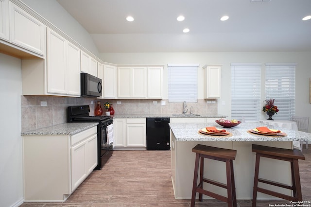 kitchen with black appliances, light hardwood / wood-style floors, white cabinets, and a kitchen island