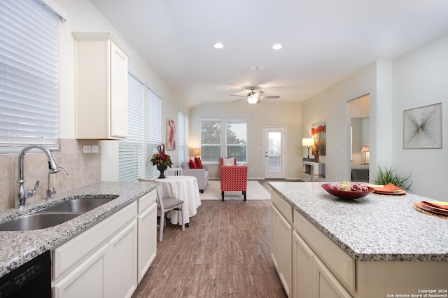 kitchen featuring light stone countertops, sink, ceiling fan, black dishwasher, and light hardwood / wood-style floors