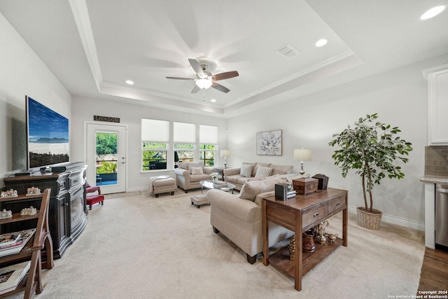 carpeted living room featuring ceiling fan, a tray ceiling, and ornamental molding