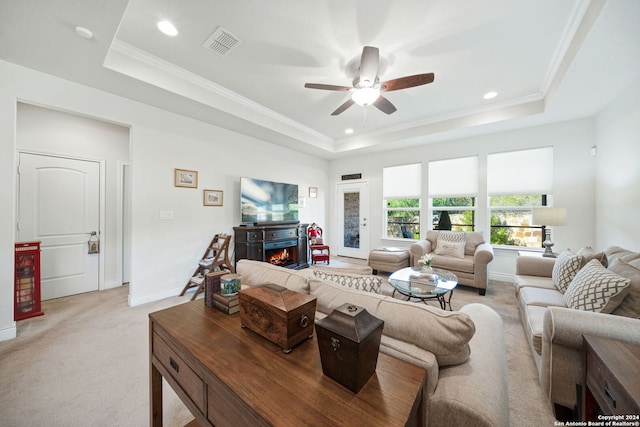 living room featuring ceiling fan, light colored carpet, and a tray ceiling