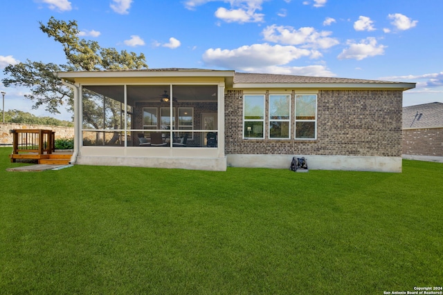 rear view of property featuring ceiling fan, a sunroom, and a lawn