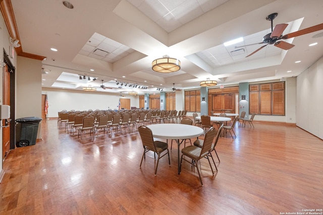 dining room featuring a raised ceiling, ceiling fan, light hardwood / wood-style flooring, and coffered ceiling