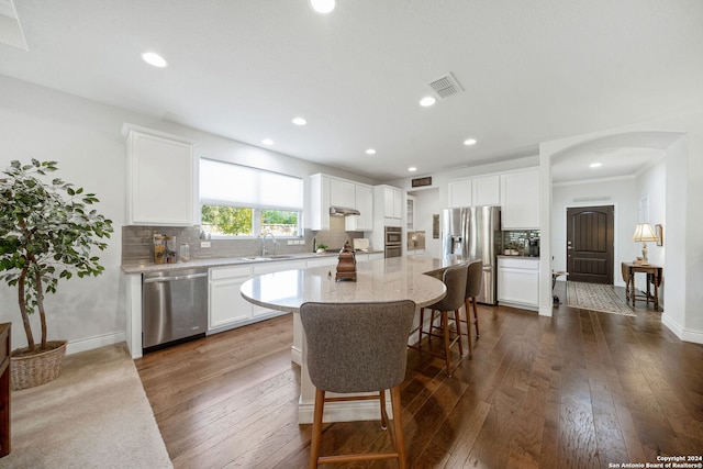 kitchen with stainless steel appliances, sink, white cabinetry, tasteful backsplash, and a kitchen island