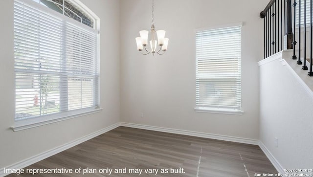 unfurnished dining area featuring a healthy amount of sunlight, dark hardwood / wood-style flooring, and an inviting chandelier