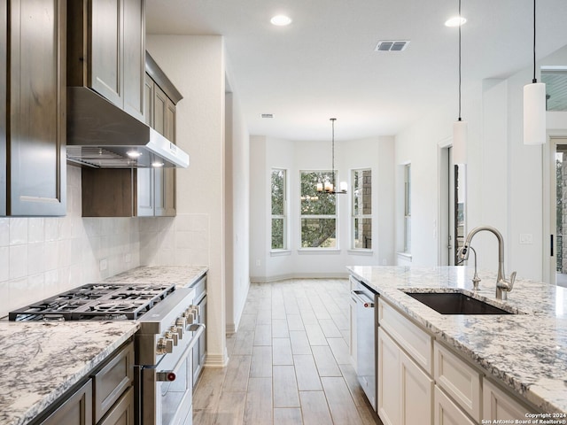 kitchen featuring sink, light stone counters, a notable chandelier, pendant lighting, and appliances with stainless steel finishes