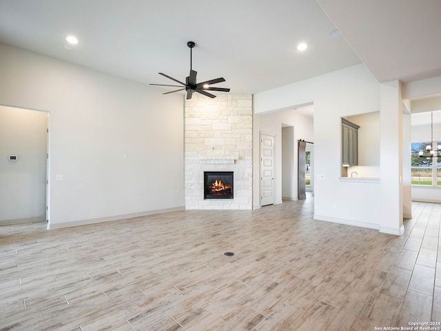 unfurnished living room featuring light wood-type flooring, a stone fireplace, and ceiling fan