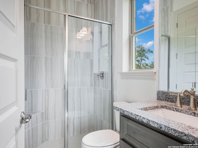 bathroom featuring vanity, a shower with shower door, and toilet