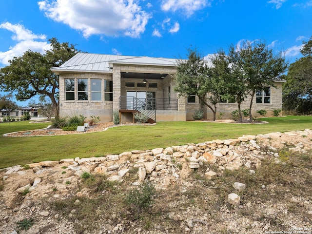 back of property featuring ceiling fan and a yard