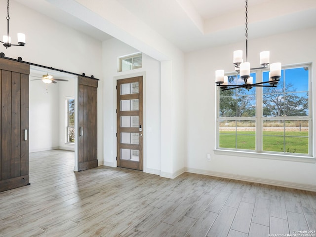 foyer with a barn door, a wealth of natural light, and light hardwood / wood-style flooring