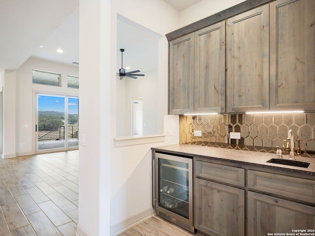 kitchen with backsplash, wine cooler, sink, and light hardwood / wood-style floors