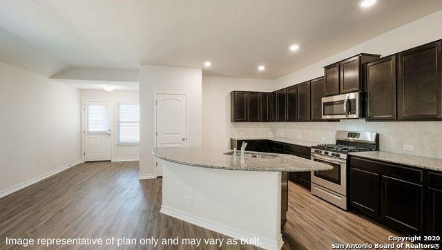 kitchen featuring light stone countertops, sink, stainless steel appliances, hardwood / wood-style floors, and a center island with sink