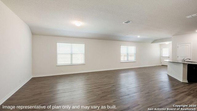 unfurnished living room with sink, plenty of natural light, dark hardwood / wood-style flooring, and a textured ceiling