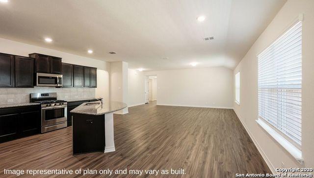 kitchen with sink, dark wood-type flooring, stainless steel appliances, tasteful backsplash, and an island with sink