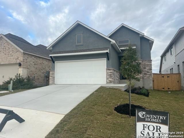 view of front of home with brick siding, stucco siding, a front yard, a garage, and driveway