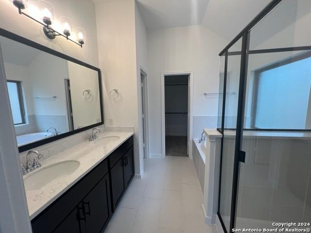 bathroom with lofted ceiling, a garden tub, a shower stall, and a sink