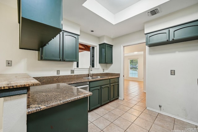 kitchen featuring green cabinets, light tile patterned floors, sink, and dark stone counters