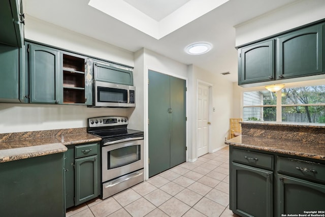 kitchen featuring stainless steel appliances, green cabinetry, and light tile patterned flooring