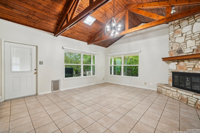 unfurnished living room with a skylight, light tile patterned floors, a fireplace, beamed ceiling, and wood ceiling