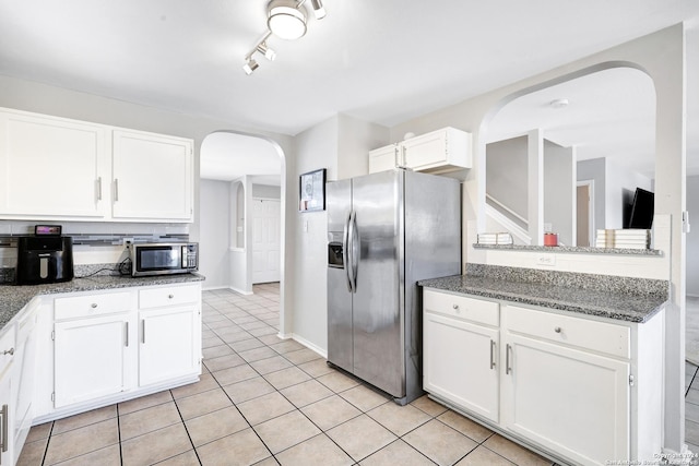 kitchen featuring white cabinetry, rail lighting, stainless steel appliances, dark stone counters, and light tile patterned floors