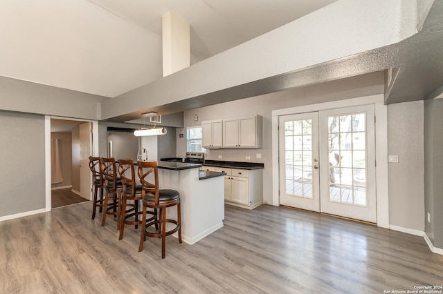 kitchen with white cabinets, a breakfast bar, and hardwood / wood-style flooring