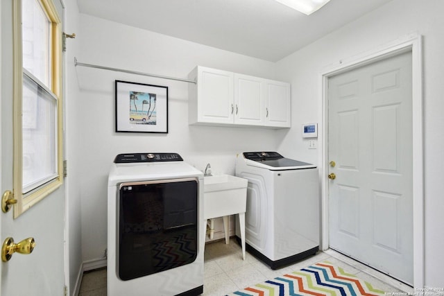 clothes washing area featuring cabinets and separate washer and dryer