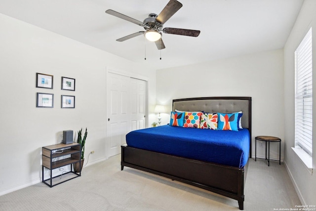 carpeted bedroom with ceiling fan and a closet