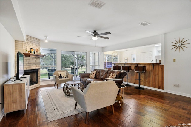 living room with ceiling fan, dark wood-type flooring, and a brick fireplace