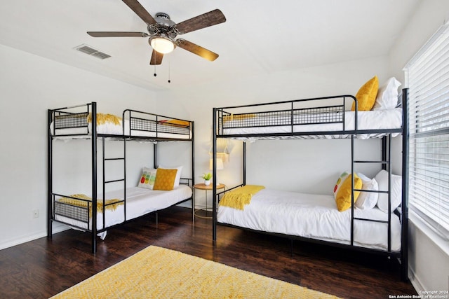 bedroom featuring ceiling fan, dark hardwood / wood-style floors, and multiple windows