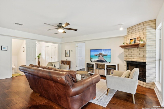 living room featuring ceiling fan, dark hardwood / wood-style floors, and a brick fireplace