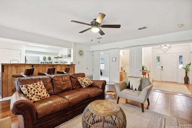 living room featuring ceiling fan with notable chandelier and light wood-type flooring